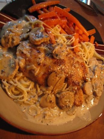 a plate with pasta, carrots and meat on it sitting on a wooden table