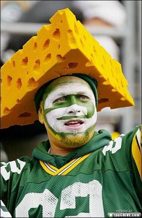 a man with his face painted in green and yellow is holding a cheese slice on his head