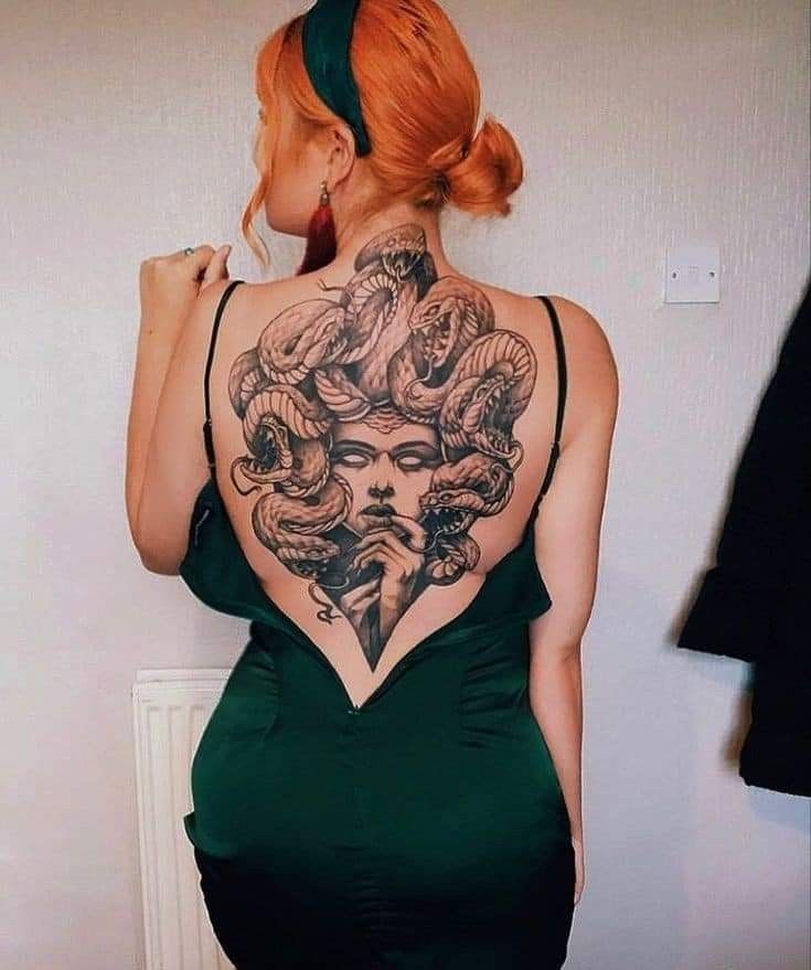 a woman in a green dress with tattoos on her back