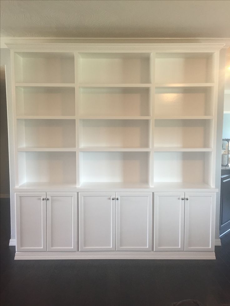 an empty room with white bookshelves and cabinets