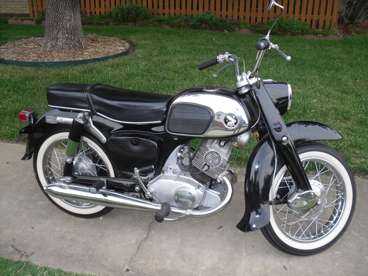 a black and silver motorcycle parked on top of a cement sidewalk next to a tree