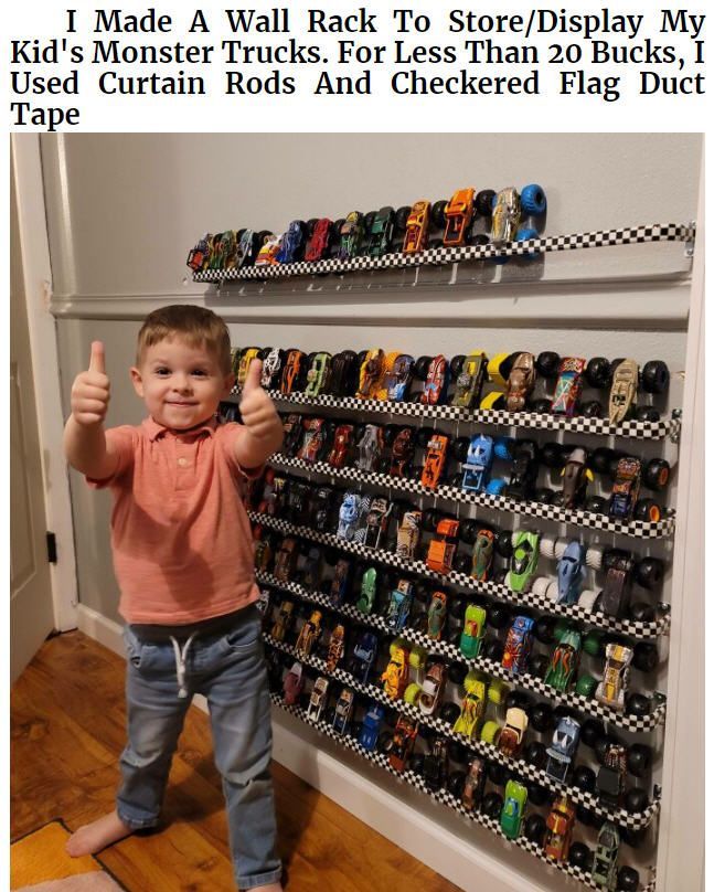 a little boy standing in front of a rack with cars on it and giving the thumbs up