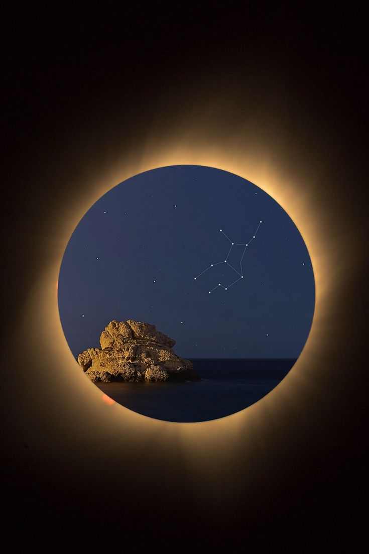 the moon is seen through an eclipse as it passes over a rocky outcropping