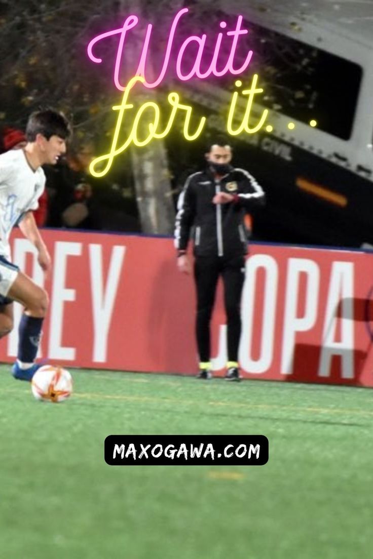 a man kicking a soccer ball on top of a green field next to a neon sign that says wait for it