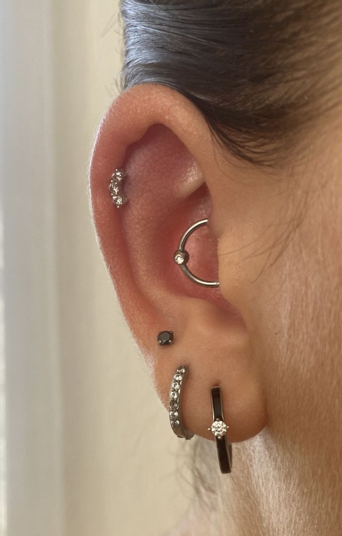 a woman's ear with three different piercings