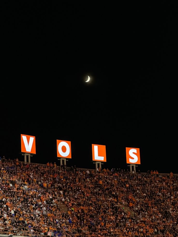 a stadium filled with lots of people sitting in the bleachers at night time