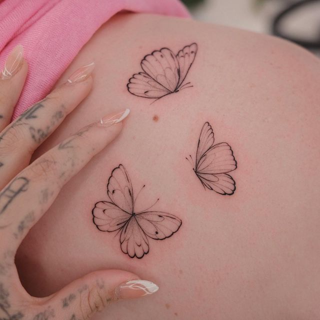 a pregnant woman's belly with three butterflies on her stomach and the top half of her abdomen