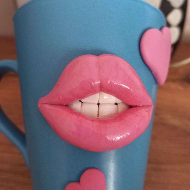 a blue coffee mug with pink lips and hearts on the inside is sitting on a table