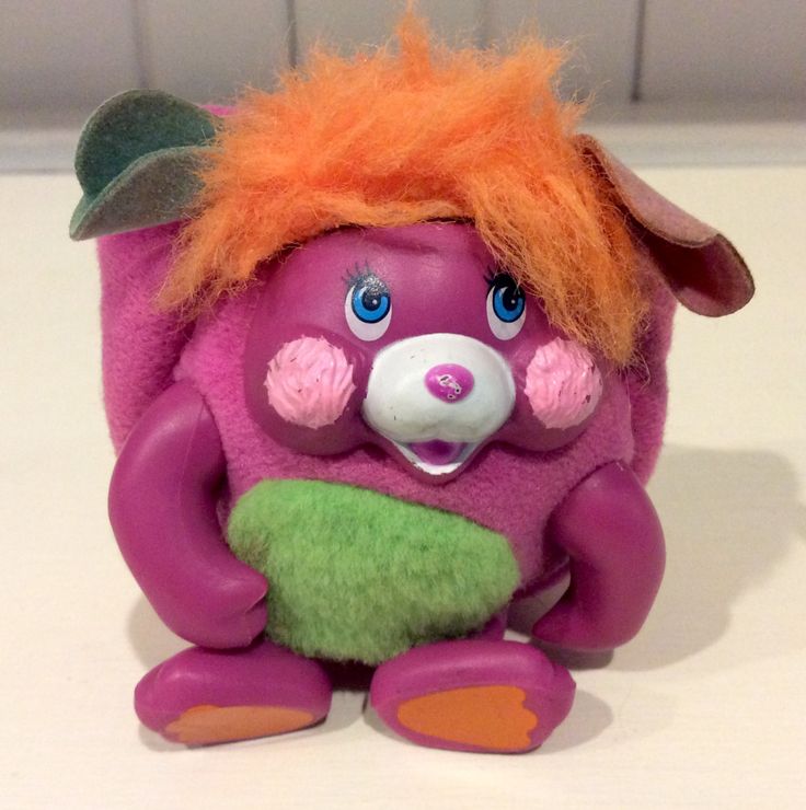 a purple troll with orange hair sitting on a table