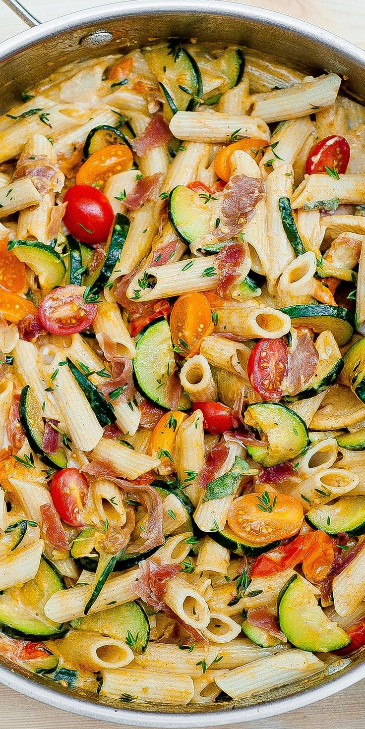 a pan filled with pasta and vegetables on top of a wooden table