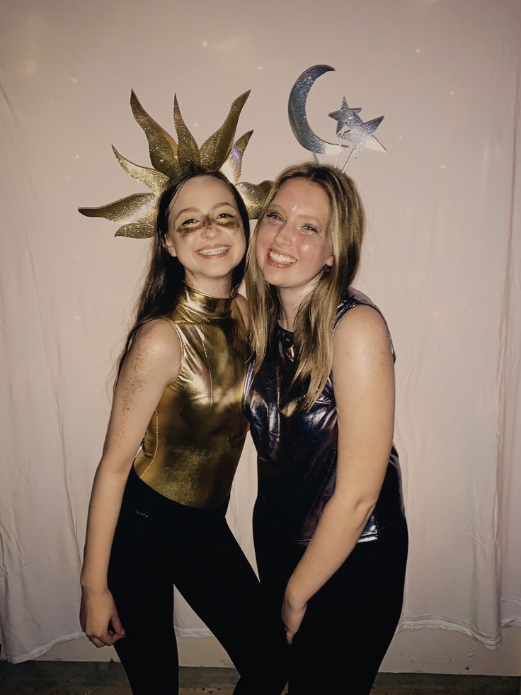 two women pose for the camera in front of a backdrop with stars and moon decorations