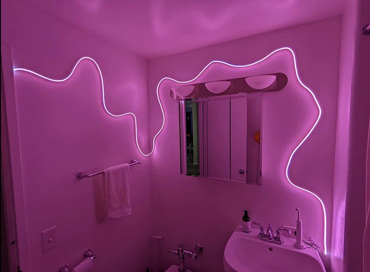 a bathroom with pink lighting on the walls and sink in the corner, along with a mirror