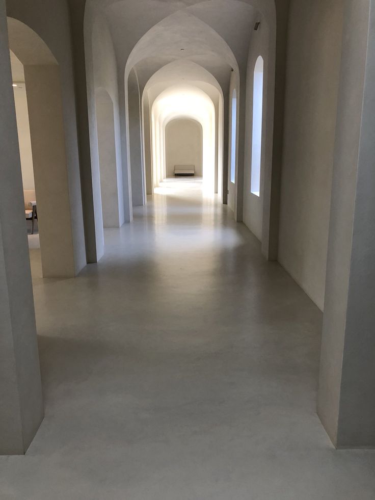 an empty hallway with white walls and arches