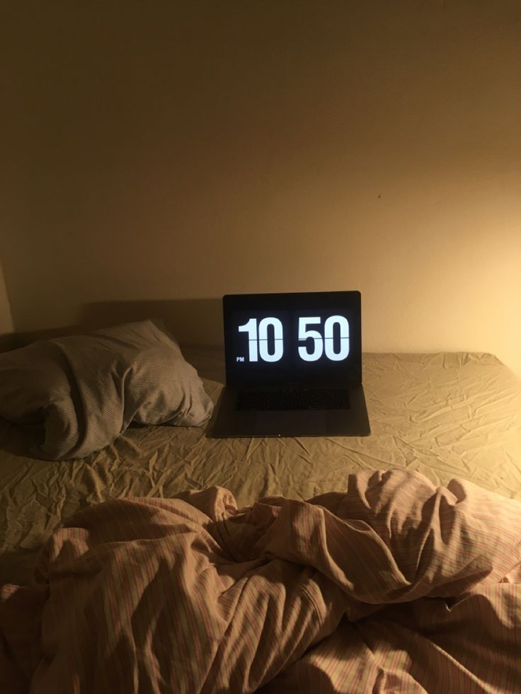 an alarm clock sitting on top of a bed next to a night stand and pillow