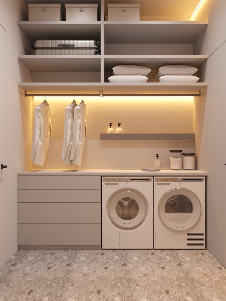 a washer and dryer in a small room with shelves on the wall above them