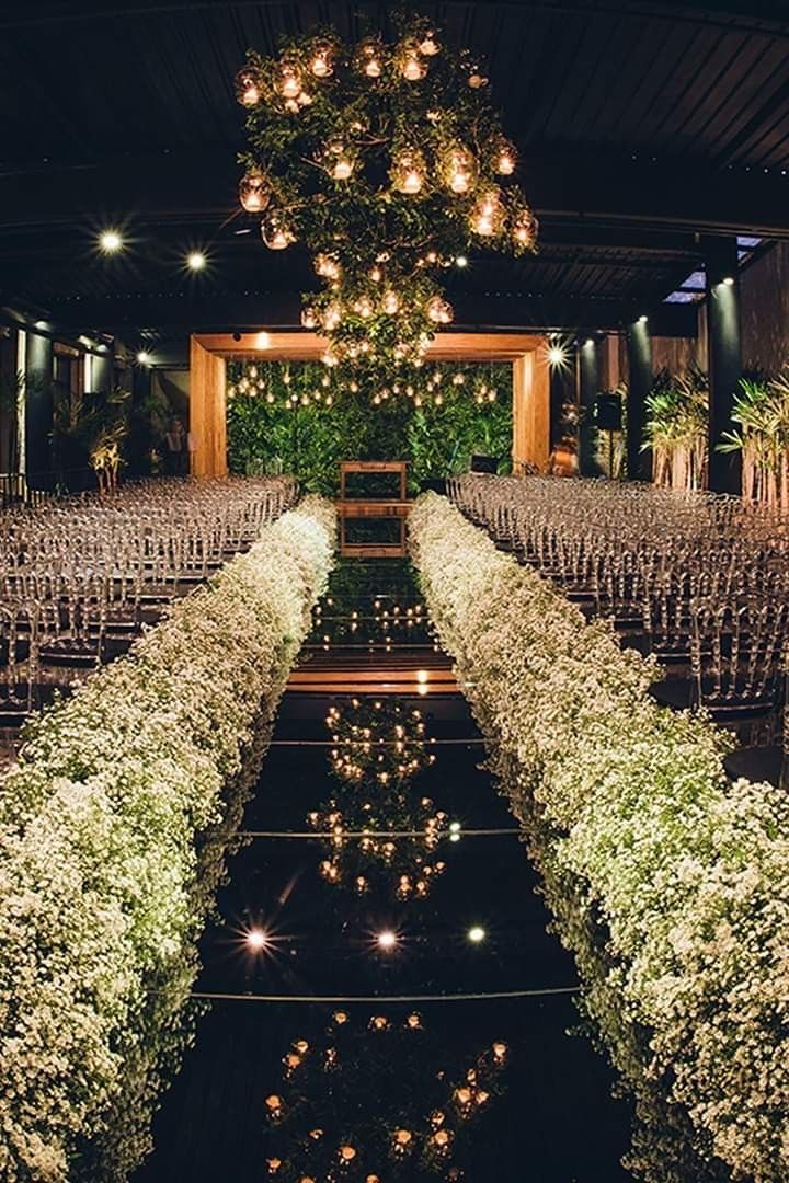 an indoor ceremony with rows of chairs and lights