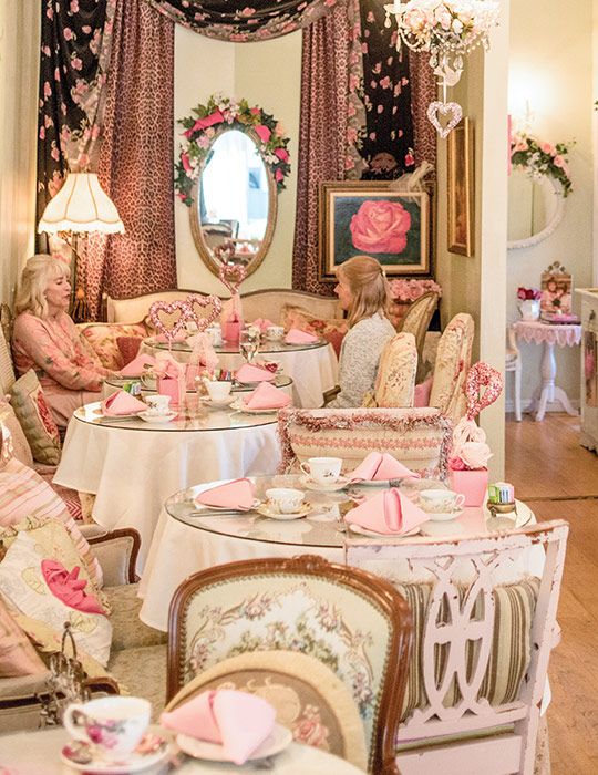 several women sitting at tables in a fancy dining room with pink and white decor on the walls