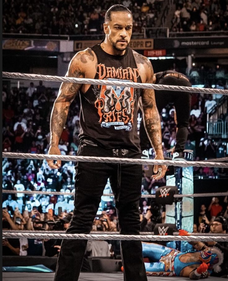 the rock standing in front of an audience at a wrestling match with his hands on his hips