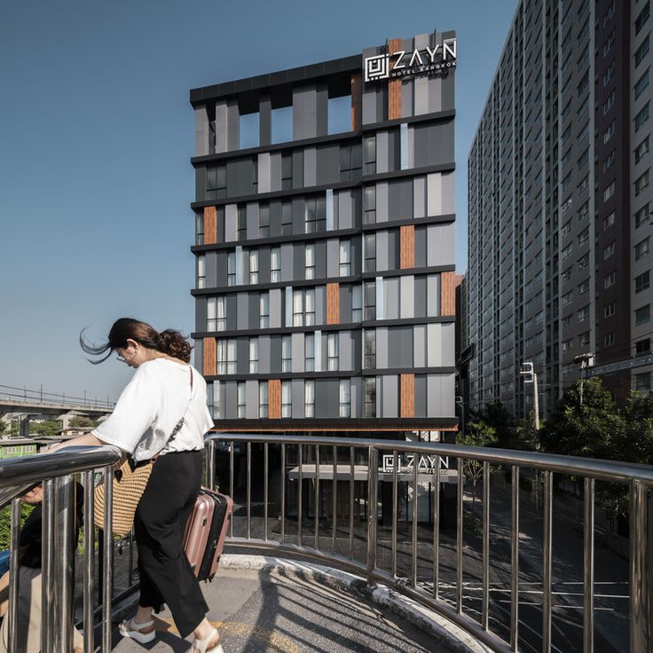 a woman walking down a balcony next to a tall building