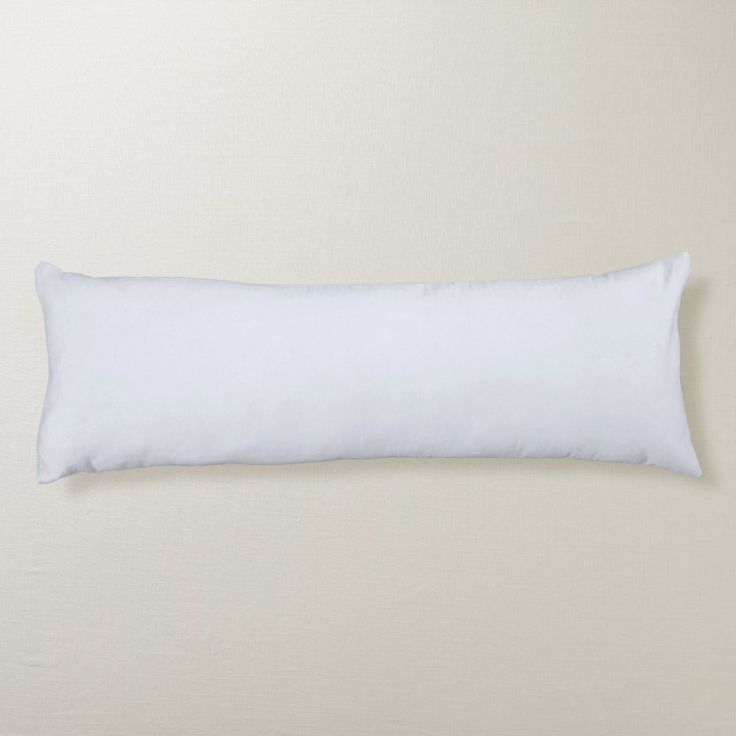 a white pillow sitting on top of a bed next to a beige wall and floor