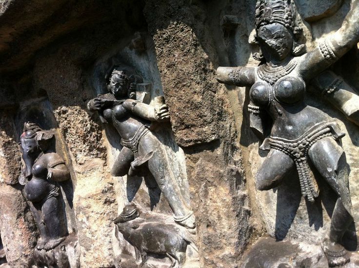 two statues in the shape of people climbing up and down on rocks, one holding a bird