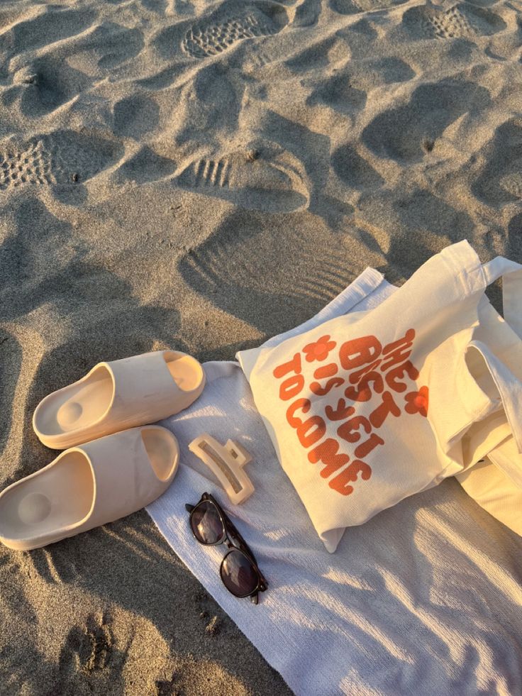 some shoes and sunglasses are laying on the sand