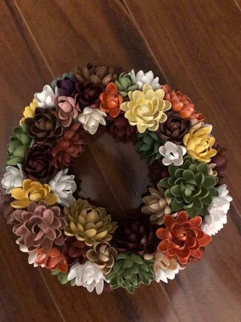 a wreath made out of fake flowers on a wooden floor in front of a door