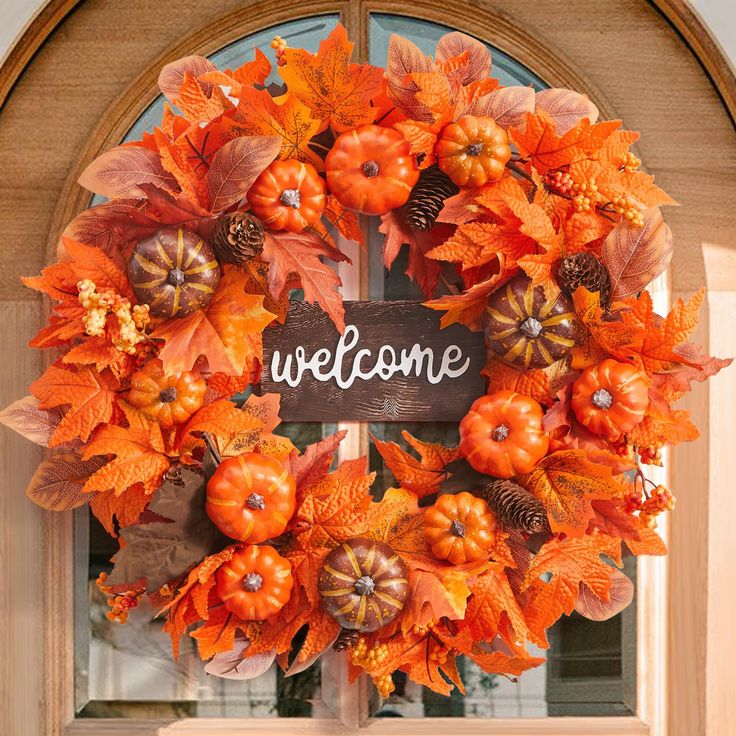 an orange wreath with pumpkins and leaves is hanging on the front door to welcome guests