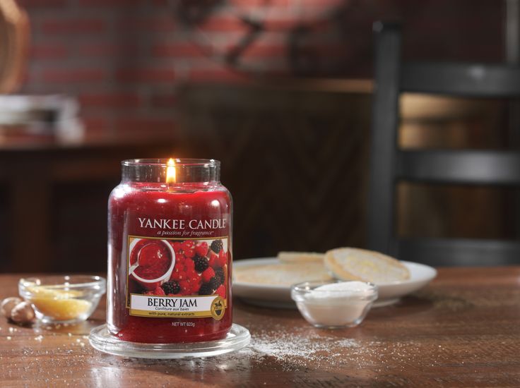 a red candle sitting on top of a wooden table next to a plate of bread