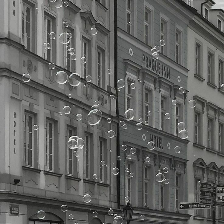 black and white photograph of bubbles floating in the air over a city street with tall buildings