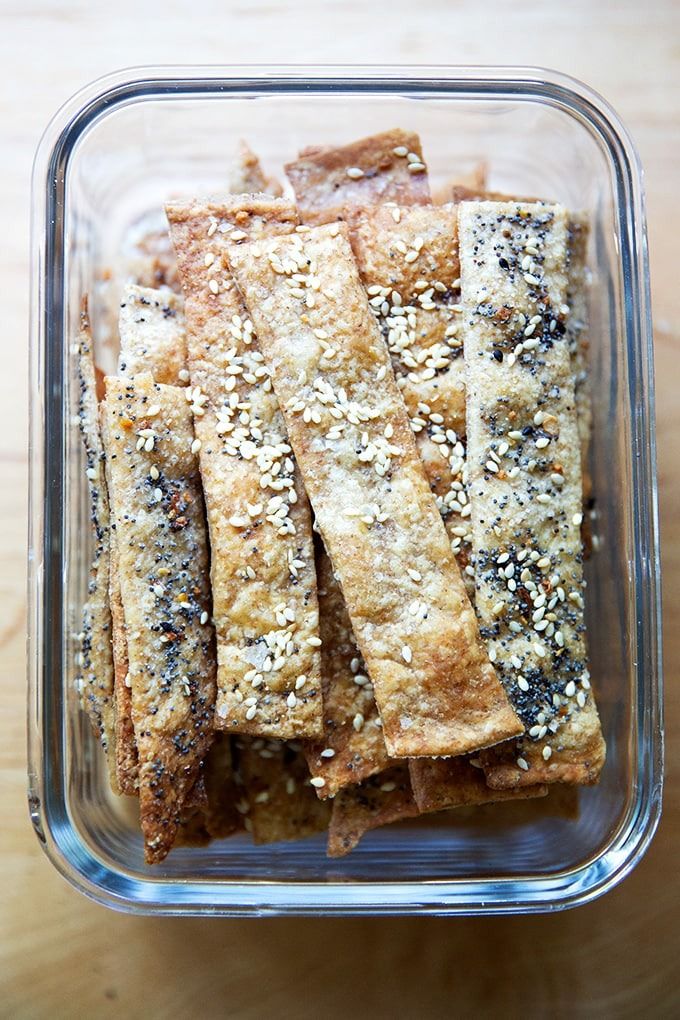 an image of food in a glass dish on the table with chopsticks and sesame seeds