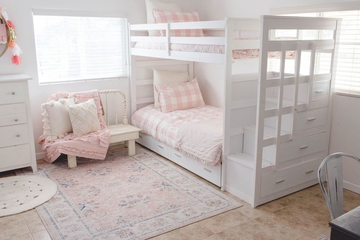 a bedroom with bunk beds, dressers and a rug on the floor in front of it