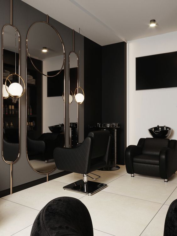 a black and white salon with mirrors, chairs and lights on the wall in front of it