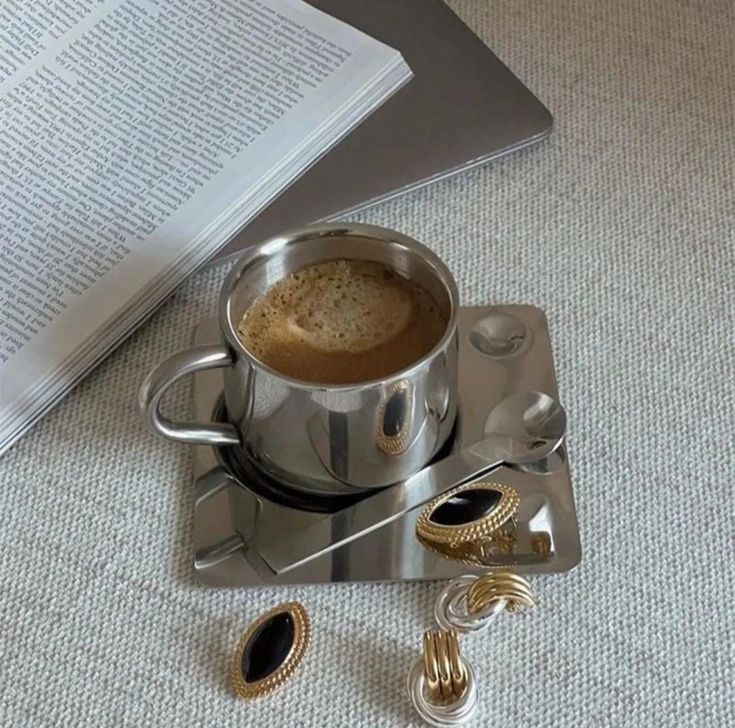 a cup of coffee sitting on top of a saucer next to an open book