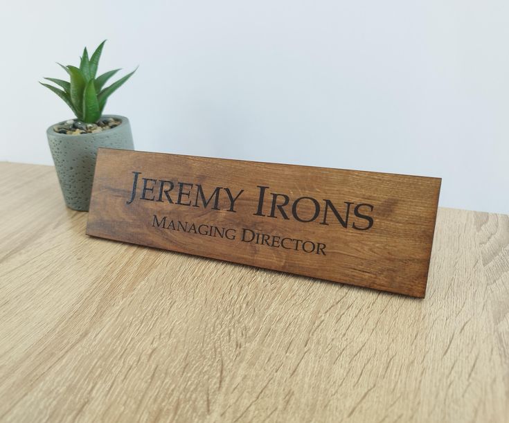 a wooden sign sitting on top of a table next to a potted plant