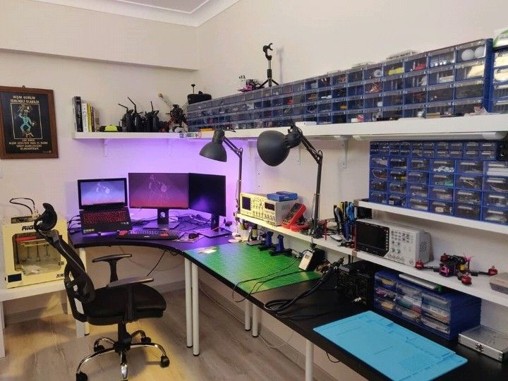 there is a desk with two computer monitors on it and many other items in the room