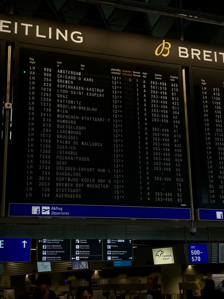 an airport terminal with a large screen displaying the flight times and departures on it