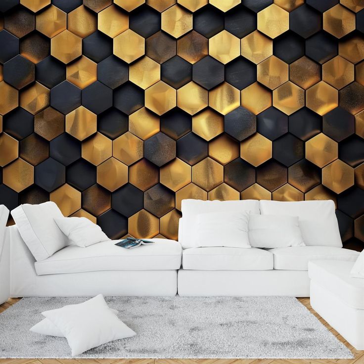 a white couch sitting in front of a wall covered in gold hexagon tiles