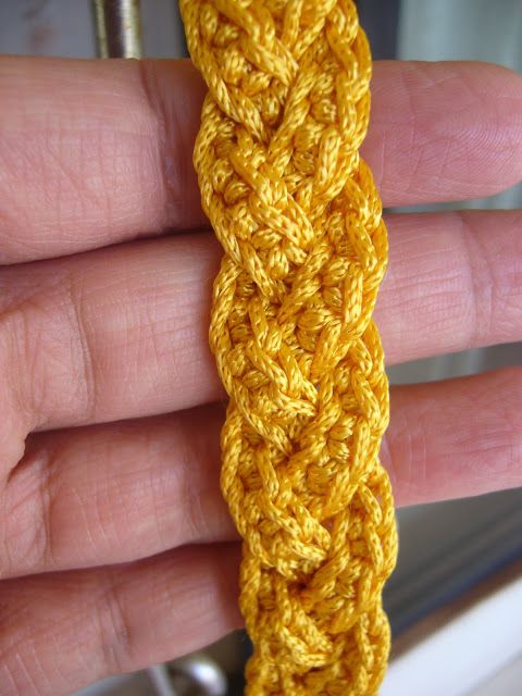 a hand holding a yellow crochet piece in it's left hand,