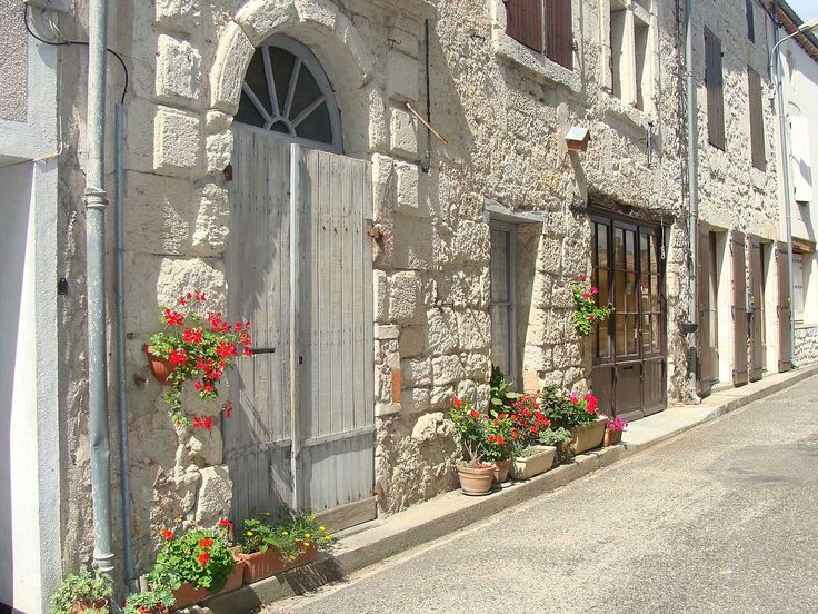 an old stone building with potted flowers on the outside and doors in between it