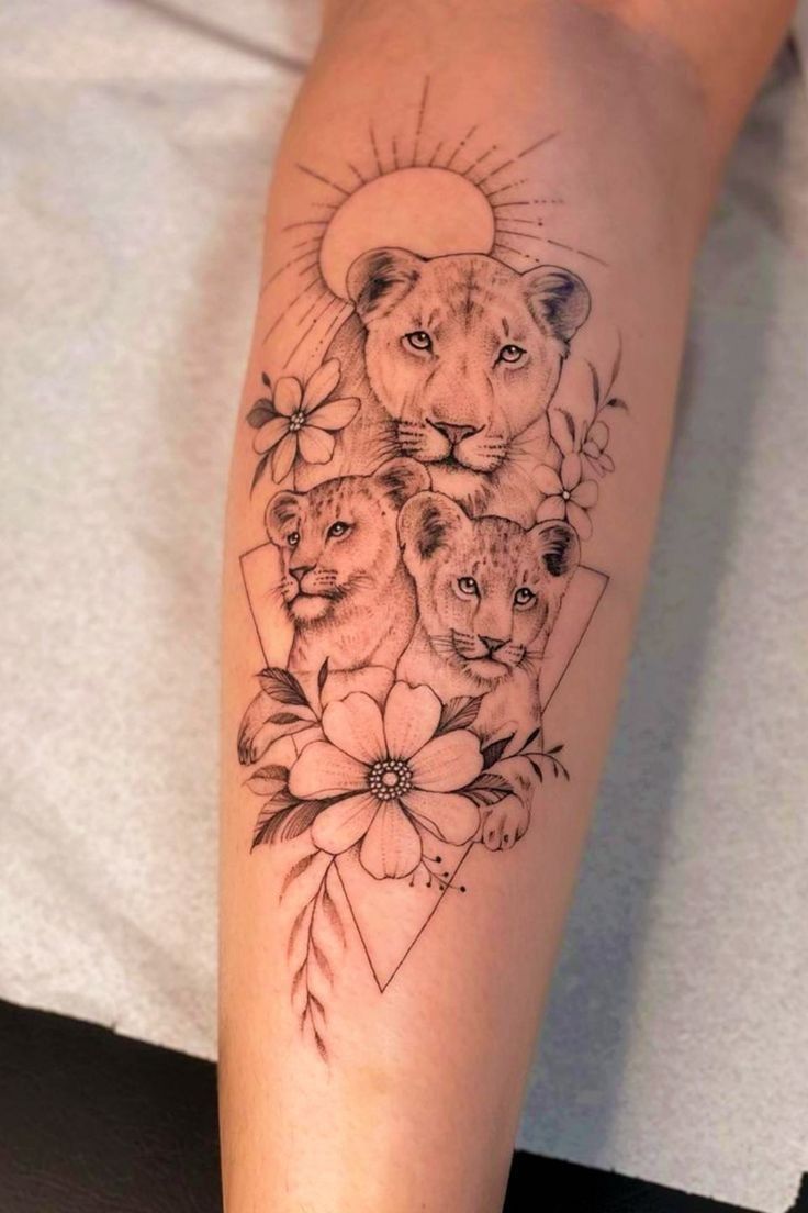 a woman's leg with tattoos on it and two lions in the middle of her arm