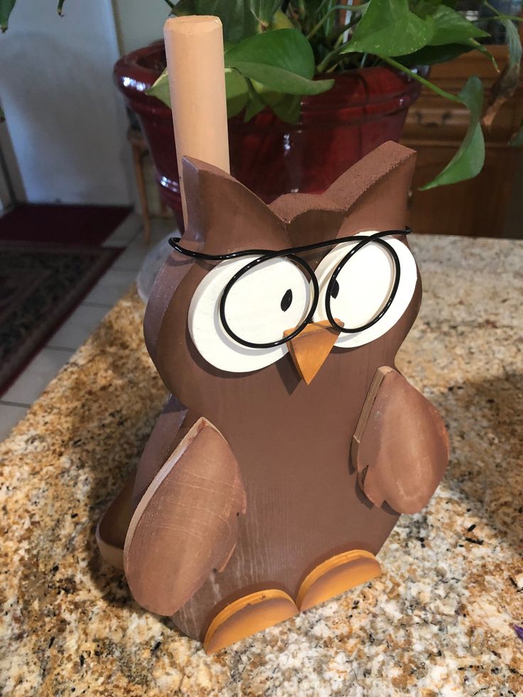 an owl statue sitting on top of a counter next to a potted plant