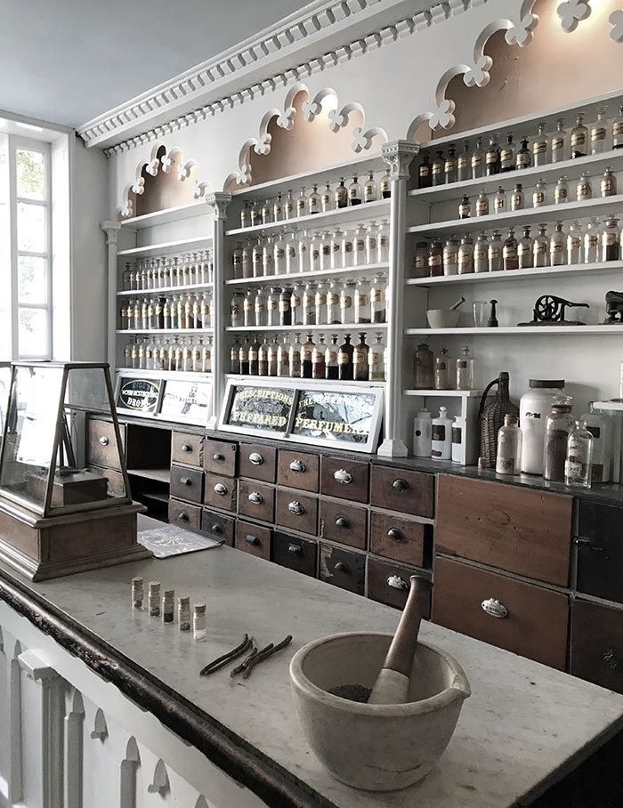 an old fashioned pharmacy with lots of bottles on the shelves and drawers in front of it