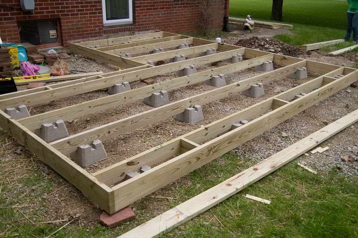 an unfinished garden bed with concrete blocks laid out on the ground in front of a brick building