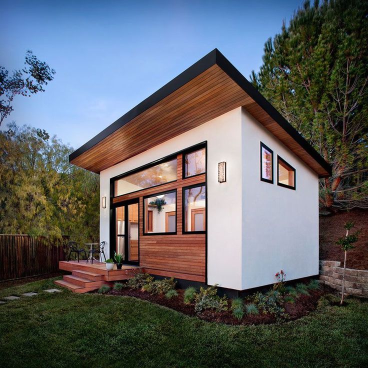 a small white house sitting on top of a lush green field