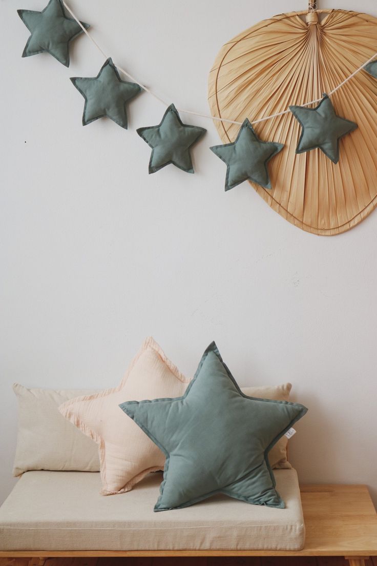 some green stars are hanging on the wall above a bed with pillows and throw pillows