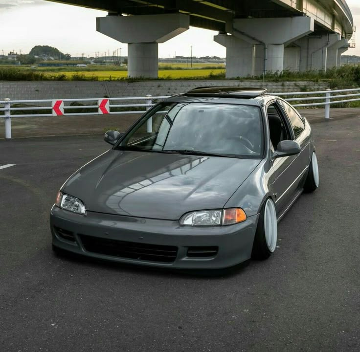 a gray car parked in front of a bridge