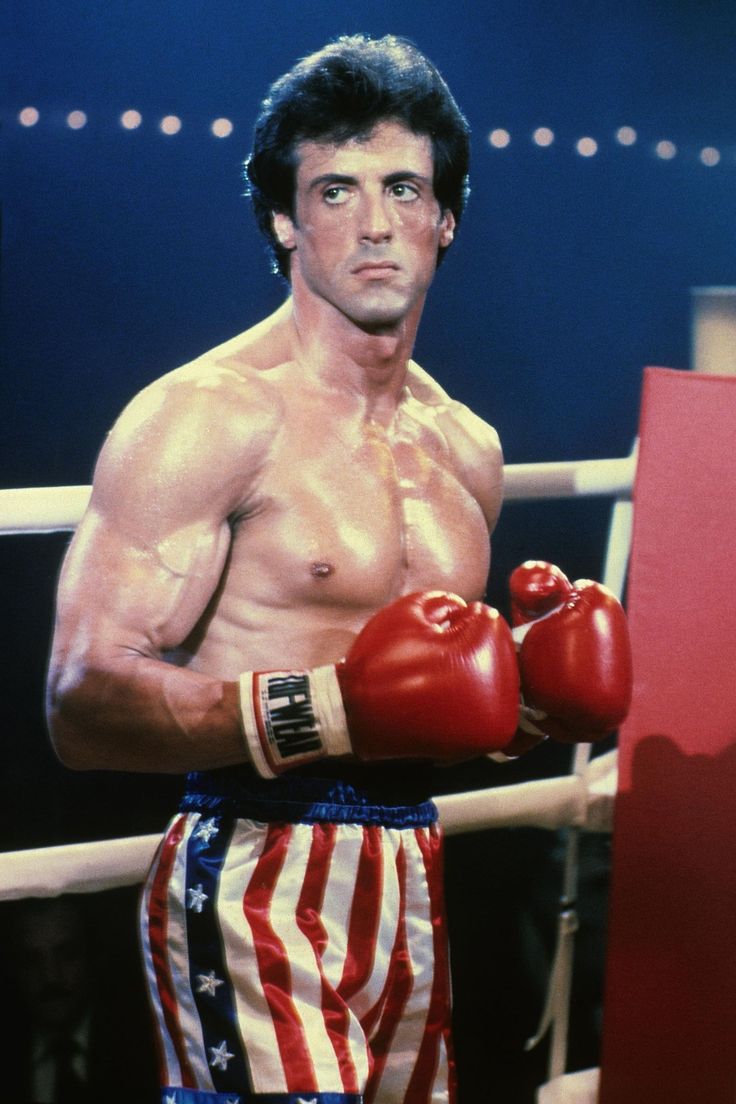 a man standing next to a boxing ring wearing red, white and blue trunks with american flags on them