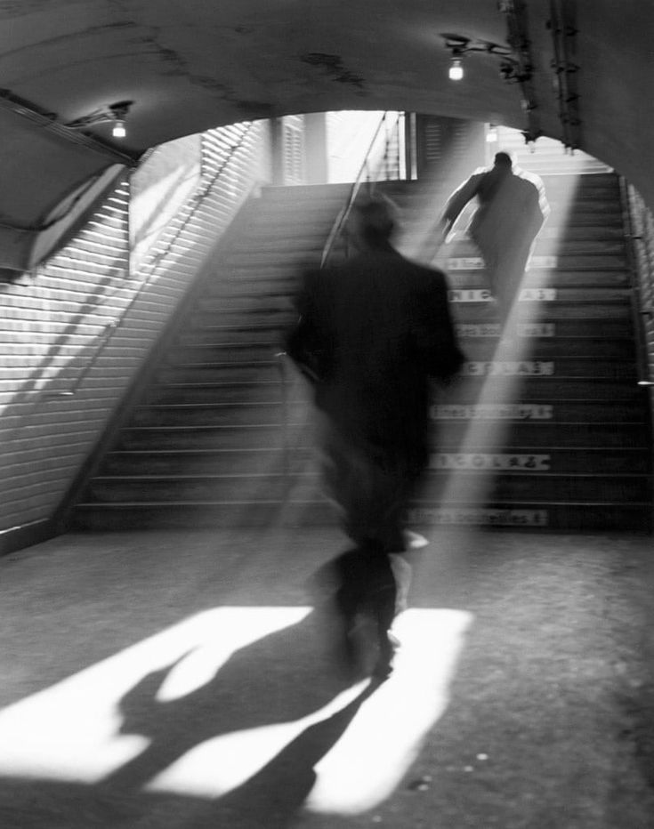 a man walking up some stairs with his shadow on the ground and light coming from behind him