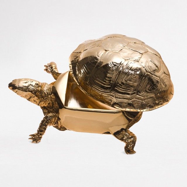 a gold turtle statue sitting on top of it's back legs in front of a white background